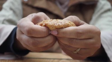 Parmağında yüzük olan ve rahat bir ortamda yakalanmış tuhaf bir pasta tutan bir adam..