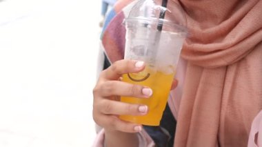 Güneşli bir öğleden sonra, bir insan ferahlatıcı bir narenciye içeceği tutar.