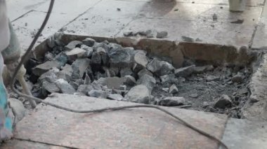 İki işçi inşaat alanındaki beton levhaları kaldırmak için matkap ve aletler kullanıyor..