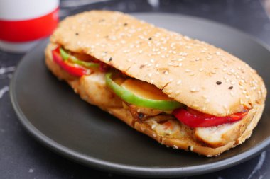 Yumuşak susamlı çöreğin içinde taze sebzelerle lezzetli bir tavuklu sandviçin tadını çıkar.