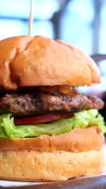 Ağzını sulandıran bir burger, sulu sığır eti, taze marul, olgun domates ve yumuşak bir çörek.