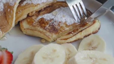 Yumuşak krepler taze muz dilimleri ve toz şekerle sıcak servis edilir.