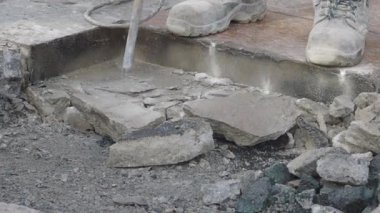 Bir işçi inşaat alanında beton döşemek için su jeti kullanıyor.