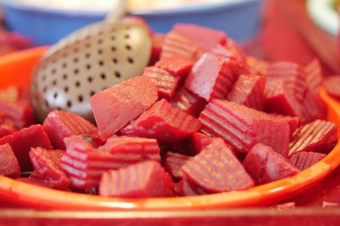 Parlak turuncu bir kasede zarif bir şekilde sergilenen enfes pancar kökü küpleri.