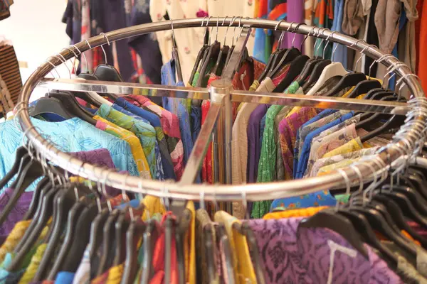 Perakende satışta dairesel bir rafta düzgünce sergilenen canlı giysilerin bir koleksiyonu.