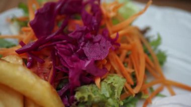 Bu renkli salata taze yeşillikler, rendelenmiş havuçlar ve çıtır çıtır mor lahanayı içerir.