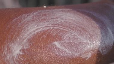 Cilt bakımını arttırmak için koluna nemlendirici krem süren biri.