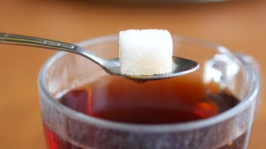 Bir küp şeker, bir bardak çayın üzerine dikkatlice yerleştirilir ve tatlı bir tat katmaya hazırlanır.