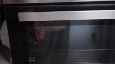 Modern bir mutfakta fırın kapısını açarken, saat 18: 20 'yi gösteriyor..