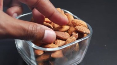 Siyah arkaplanda elle seçilen badem fıstığına yakın plan .