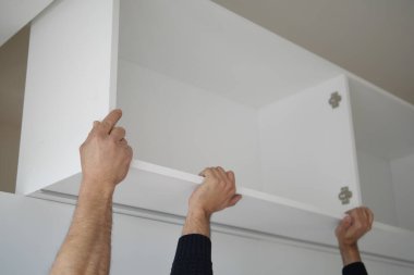 Yetenekli eller, iç dekorasyonu geliştirmek için modern beyaz bir dolap kuruyor.