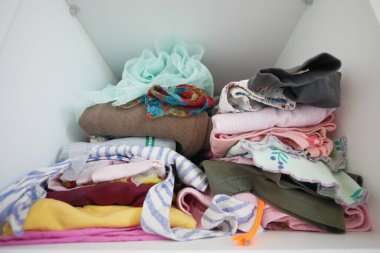 Temiz katlanmış giysileri ve kolay erişim için ayrı raflarda tekstil ürünleri olan parlak beyaz dolap.