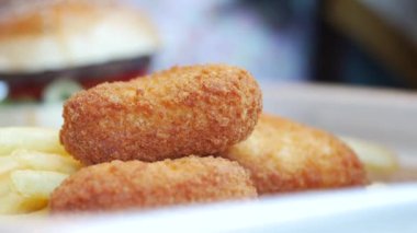 İçinde çıtır tavuk nuggetları, lezzetli patates kızartmaları ve sulu bir hamburger olan iştah açıcı bir tabak.