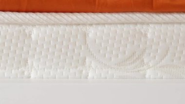 Örgü desenli ve nötr tonlu beyaz bir yatak yakın çekim görüntüsünde rahat bir deneyim sunar.