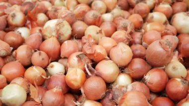 Hareketli bir pazarda canlı bir soğan yığını, kalitelerini ve tazeliklerini sergiliyor.