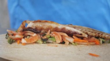Renkli sebzeli ızgara balık, çıtır bir taco kabuğunda, aromalı sosla süslenmiş.