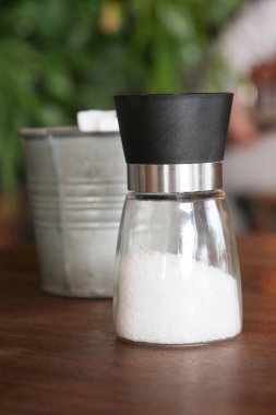 Zarif ve çağdaş bir tuz öğütücü zarif bir şekilde ahşap bir masada sergilendi.