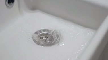 Temiz bir lavaboda dönen sabunlu suyun ayrıntılı görüntüsü..