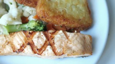 Lezzetli ızgara somon fileto yanında çıtır ve taze sebzeyle servis edilir..