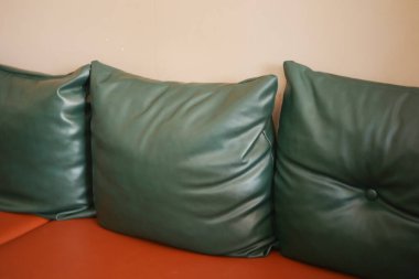 Modern turuncu koltukta zarif yeşil deri yastıklar rahat bir atmosfer yaratır.