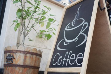 Bu büyüleyici kahve dükkanı tabelasında dumanı tüten bir fincan kahvenin davetkar bir çizimi var.