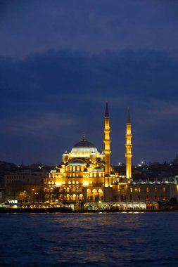 Aydınlatılmış bir cami İstanbul 'da görkemli bir şekilde gece gökyüzüne karşı duruyor ve herkesi büyülüyor.