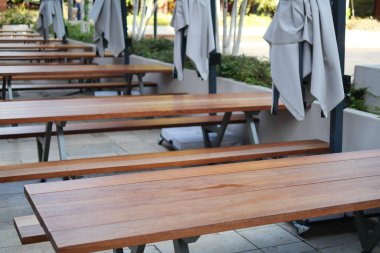 Bu şık açık hava yemek alanında gölgeler için ahşap masalar ve büyük şemsiyeler var.