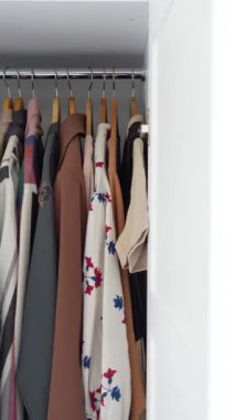 Modern bir dolap içinde düzgün bir şekilde düzenlenmiş çeşitli giyim ürünleri.