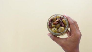 Turuncu arkaplanda yeşil zeytin kavanozunun üst görüntüsü 