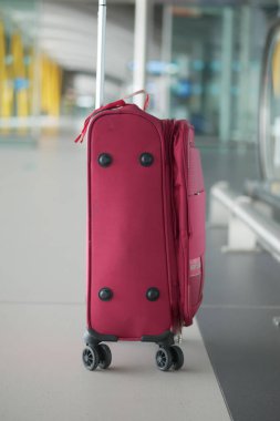 A vibrant pink suitcase is resting comfortably in a modern airport setting, adding a pop of color clipart