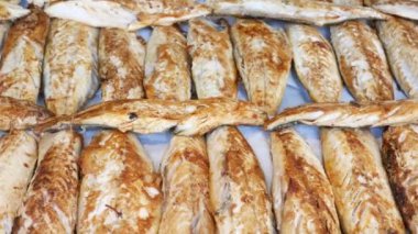 Pazar ortamında sergilenen çeşitli kurutulmuş ve ızgara balıklardan oluşan canlı ve renkli bir sıra.