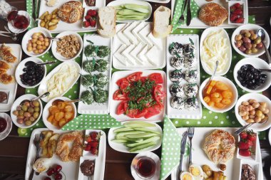 Çeşitli Akdeniz yemekleri olan iştah açıcı bir masa. Taze meyve, sebze ve peynir sergileniyor. Brunch için ideal. Canlı renkler sıcaklığı ve konukseverliği ifade eder.