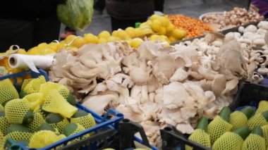 Kalabalık bir yerel pazarda renkli bir dizi taze mantar ve turunçgil meyvesi