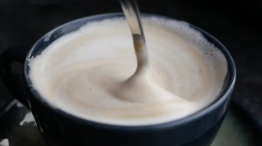 İnsan, kaşıkla kahve karıştırır.