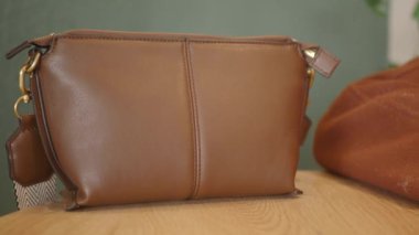 Güzel cilalanmış ahşap bir yüzey üzerinde zarif bir şekilde kahverengi deri bir çanta sergilenir.