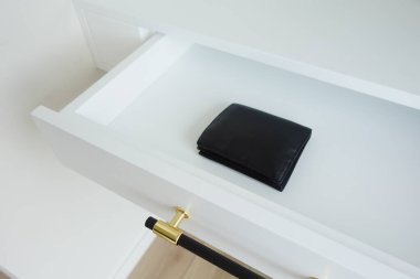 Nefis bir el yapımı, parlak siyah bir cüzdan el değmemiş ve temiz beyaz bir çekmecede duruyor.