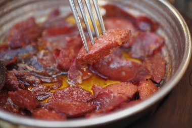 Tahta bir masada tavada kahvaltı sosisi pişirmek.,