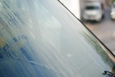 Bulanık bir etki yaratan, yağmur damlaları içeren sisli bir ön camın yakın görüntüsü