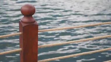 Yıpranmış ahşap bir direk, sakin ve rahatlatıcı suyun yanında halat hatlarıyla eşleştirilmiş.