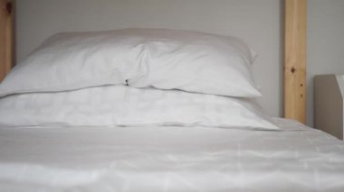 Beyaz yatak ve kabarık yastıklarla süslenmiş huzurlu ve huzurlu bir yatak.