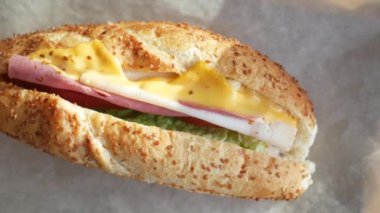 Bu lezzetli sandviçte jambon, peynir ve marul gibi taze sebzeler var.