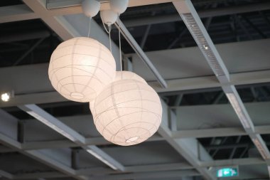 Modern bir tavan tasarımına asılmış üç adet modern beyaz fener var.