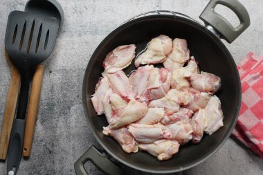 Taze ve çiğ tavuk kanatları hazır ve tavada ustalıkla pişirilmeye hazır.