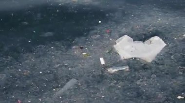 Çevresel sorunların altını çizerek atık ve molozlarla dolu kirlenmiş bir su yüzeyi.