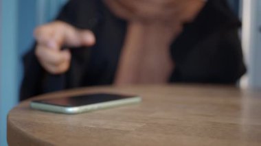 Adam el masadan akıllı telefon alıyor.