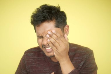 Adam, parlak sarı arka planda yüzle yüzünü kapatarak hayal kırıklığını gösteriyor..