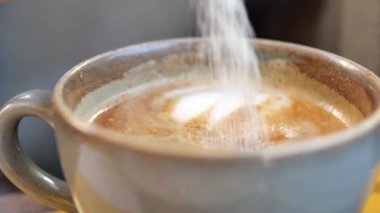 Beyaz şeker kahve fincanındaki kağıt bir paketten dökülüyor. .