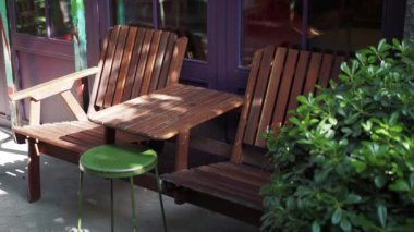Güzel ahşap sandalyeleri ve canlı yeşil taburesi olan büyüleyici bir açık hava oturma alanı.