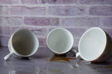 Üç kahve fincanı ters çevrilmiş. Alttaki yüzeyi kaplayan bir sızıntıyla sonuçlanmış.