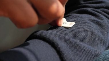Koyu renk kumaştan parmaklarıyla sıkışan sakızı çıkarmak..